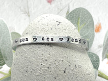 Load image into Gallery viewer, Textured Aluminium Cuff Bracelet, 10 Year Anniversary Gift, Personalised Aluminium Bracelet, Hand Stamped Adjustable Bracelet. Sun Sea Sand stamped with hearts