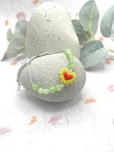 Load image into Gallery viewer, Small peridot stone bracket featuring a red heart charm on a light background with eucalyptus leaves.