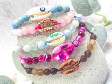 Load image into Gallery viewer, Colorful beaded bracelets with shell charms on a stone surface
