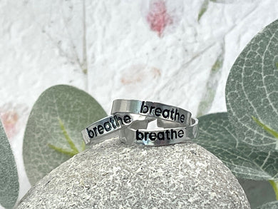 Hand stamped rings with the word breathe stamped and then enamelled in black.  Hypoallergenic and tarnish resistant.  Unisex, can be worn by all as its adjustable, can be worn by most.
Handstamped so NOT PERFECT!